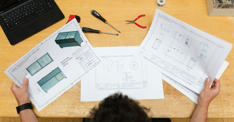 Technische Zeichnungen einer Holzvitrine – Planung und Konstruktion Technische Zeichnungen einer Holzvitrine auf einem Tisch mit Werkzeugen
