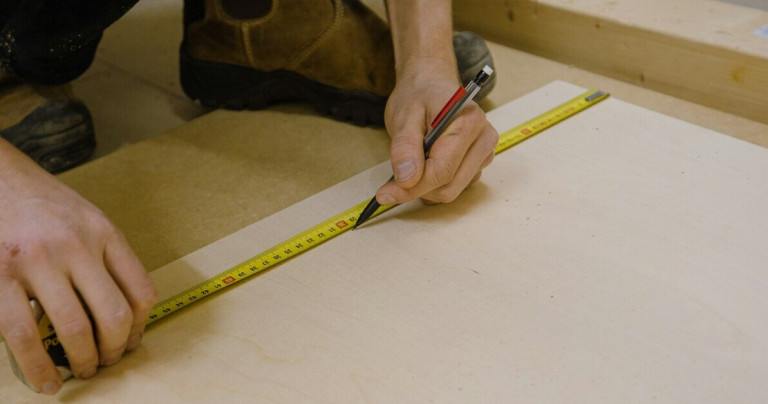 Person reißt mit Stift und Maßband auf Holz an – Handwerk, Anzeichnen und Holzarbeiten Person reißt mit Stift und Maßband auf Holz an – präzises Anzeichnen für Holzarbeiten