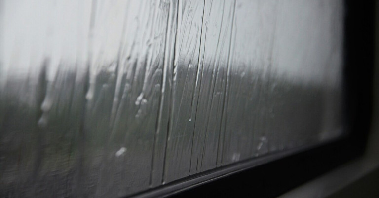 Regentropfen auf Fensterscheibe – Nahaufnahme bei Regenwetter Regentropfen auf Fensterscheibe an einem regnerischen Tag