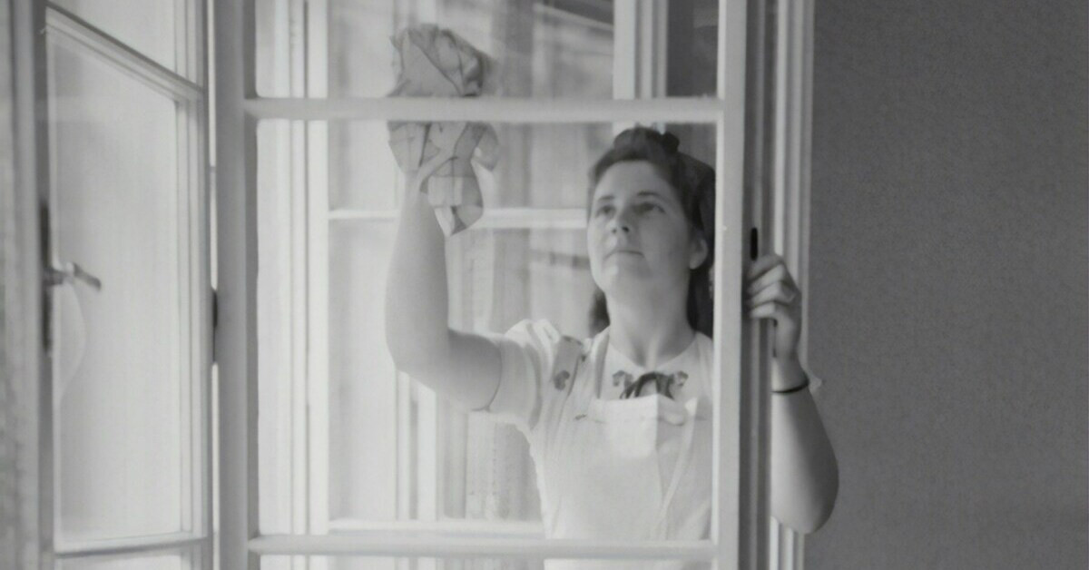 Fenster putzen – Frau reinigt Fenster mit Tuch Frau beim Fenster putzen mit einem Tuch