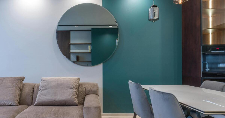 Vertikal aufgeteilte Akzentwand im Wohnzimmer mit Spiegel und moderner Einrichtung Wohnzimmer mit vertikal aufgeteilter Akzentwand in zwei Farben, rundem Spiegel und moderner Einrichtung