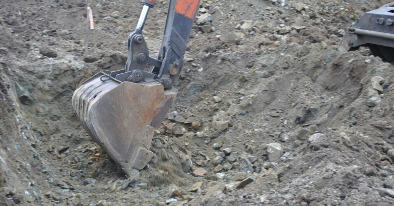 Nahaufnahme der Baggerschaufel beim Ausheben von Erde