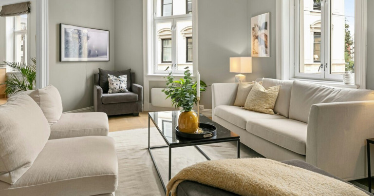 Modernes beiges Wohnzimmer mit heller Couch, Sessel, Glastisch und stilvoller Dekoration