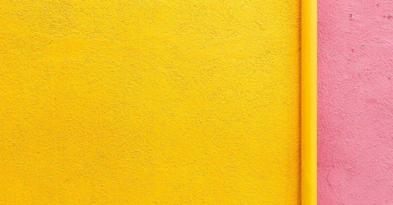 Gelb und Rosa – Strukturierte Wand in kräftigen Farben Gelbe und rosa Wandstruktur, Nahaufnahme einer farbigen Putzoberfläche