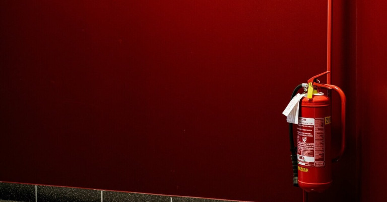 Roter Feuerlöscher – Brandschutz und Sicherheit Roter Feuerlöscher an einer roten Wand