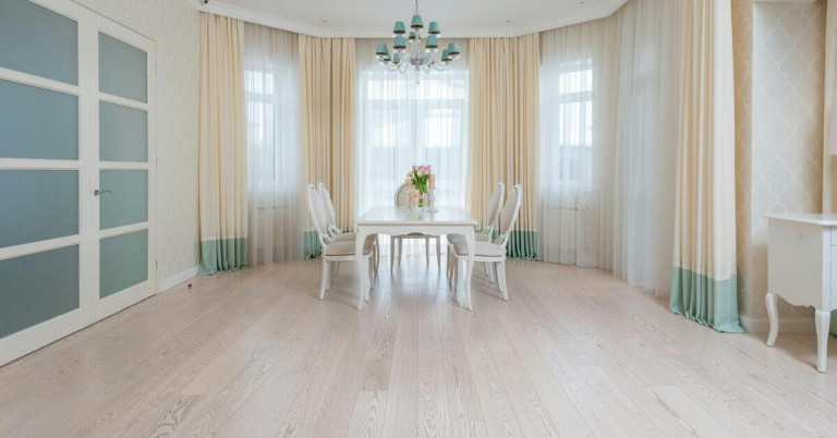 Heller Dielenboden im stilvollen Esszimmer mit weißen Stühlen und Tisch Heller Dielenboden in einem eleganten Esszimmer mit weißen Möbeln und großen Fenstern