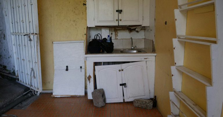 Alte und kaputte Küche mit beschädigten Schränken und abgenutztem Waschbecken