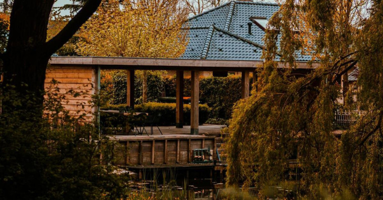 Gartenhaus aus Holz in einem gepflegten Garten mit Terrasse und Sitzbereich