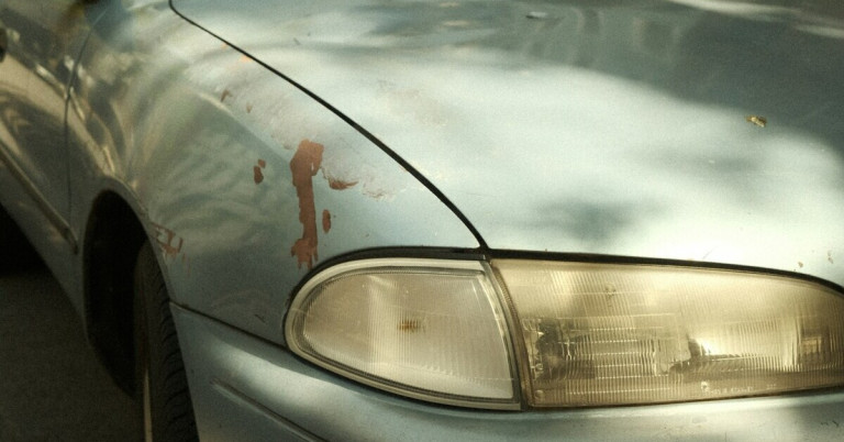 Abgeplatzter Lack an einem Auto nahe eines Scheinwerfers