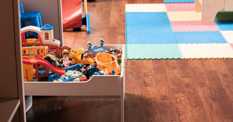 Offene Spielzeugbox mit buntem Kinderspielzeug auf Holzboden in einem Spielzimmer