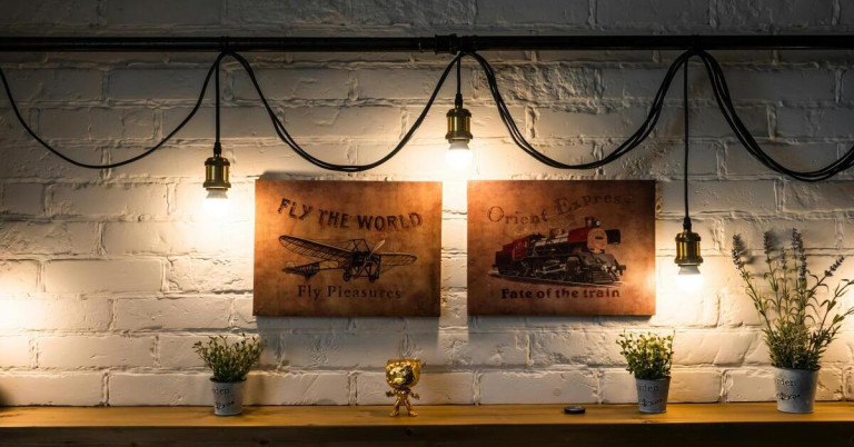 Akzentlicht und Wanddeko: Bilder von Flugzeug und Orient Express Zug, stimmungsvolle Beleuchtung Akzentlicht über Wandbilder mit Flugzeug und Orient Express Zug, dekorative Beleuchtung an weißer Backsteinwand