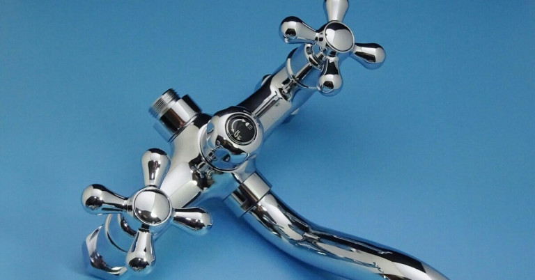 Moderne Chrom Armatur mit Kreuzgriffen für Bad oder Küche Chrom Armatur mit Kreuzgriffen vor blauem Hintergrund