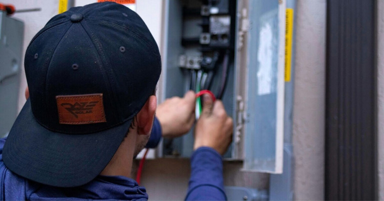 Elektroniker arbeitet an einem Schaltschrank und prüft elektrische Leitungen