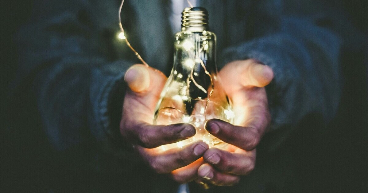 Strom sparen mit Kindern – Symbolbild einer Glühbirne in Händen, die für Energieeinsparung steht