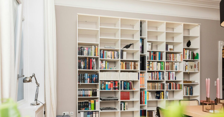 Modernes Wohnzimmer mit großem weißen Bücherregal und vielen Büchern