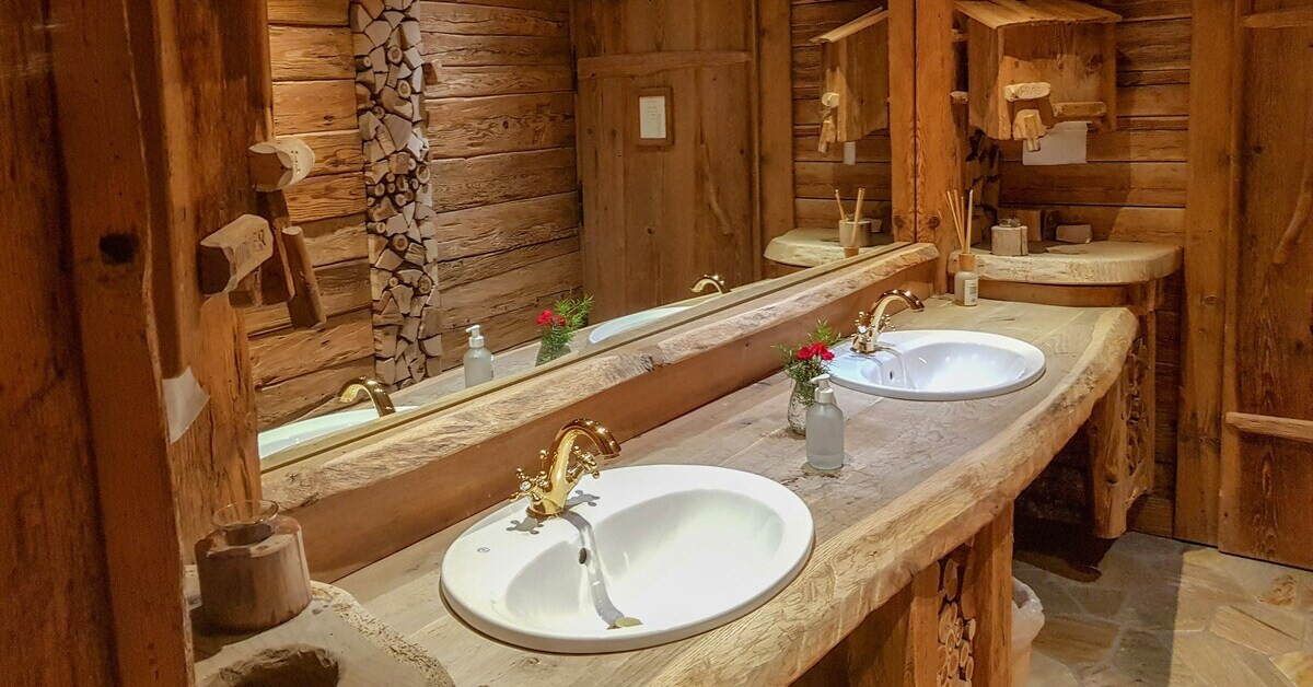 Rustikales Bad komplett aus Holz mit Waschbecken und goldenen Armaturen