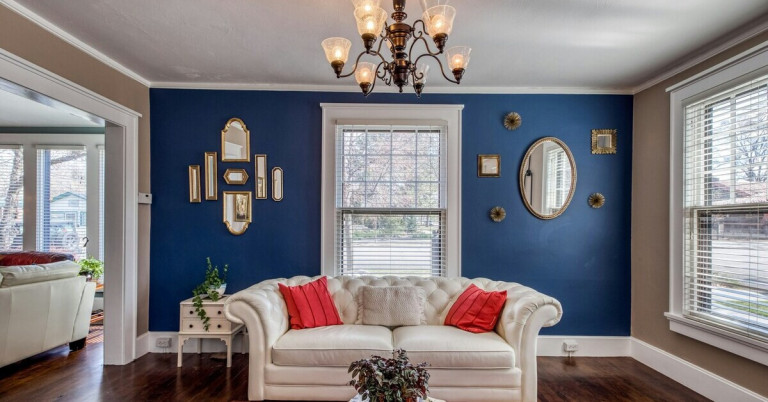 Wohnzimmer mit blauer Wand, weißem Sofa und roten Kissen