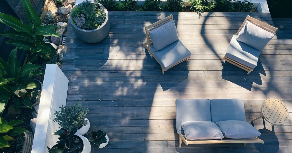 Moderne Terrasse mit Holzbelag, gemütlichen Sitzmöbeln und Pflanzen