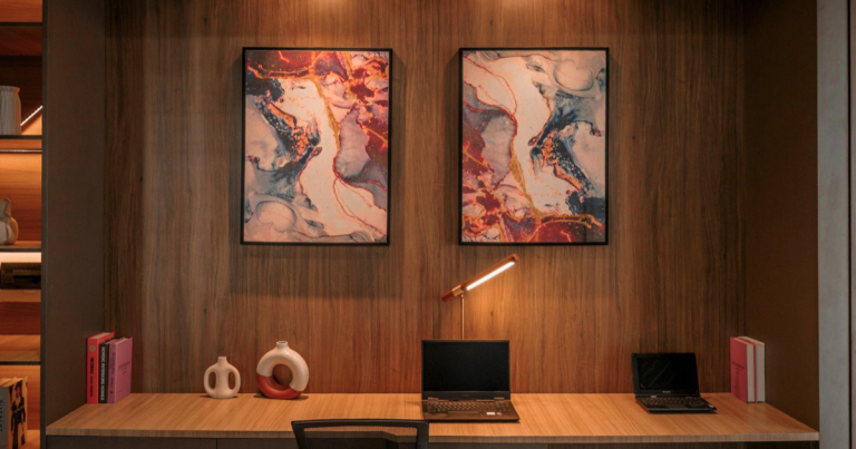 Modernes Büro im Bücherregal mit Laptop, Schreibtischlampe und abstrakten Bildern an der Wand