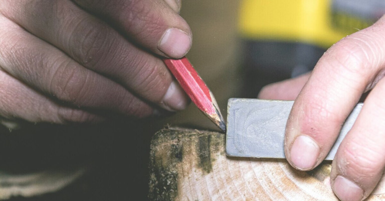 Holzarbeiten: Hand markiert Holz mit Zimmermannsbleistift