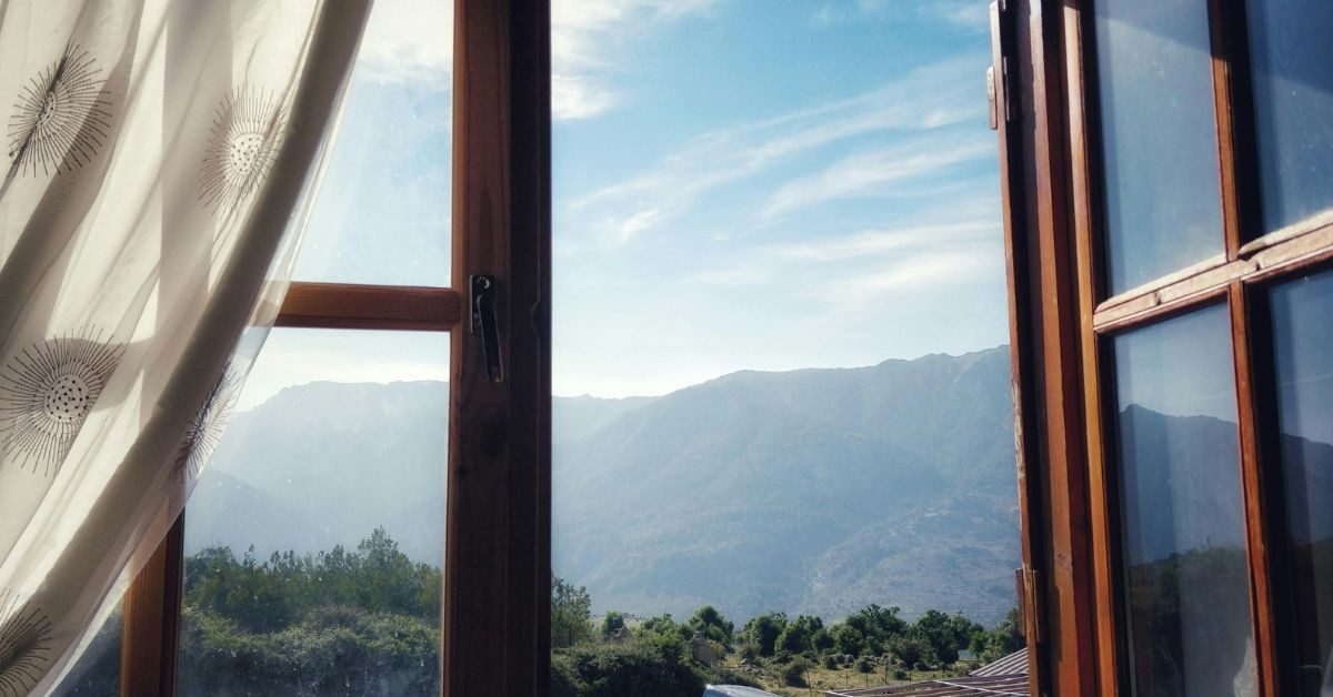 Geöffnetes Holzfenster mit Blick auf Berge und Natur