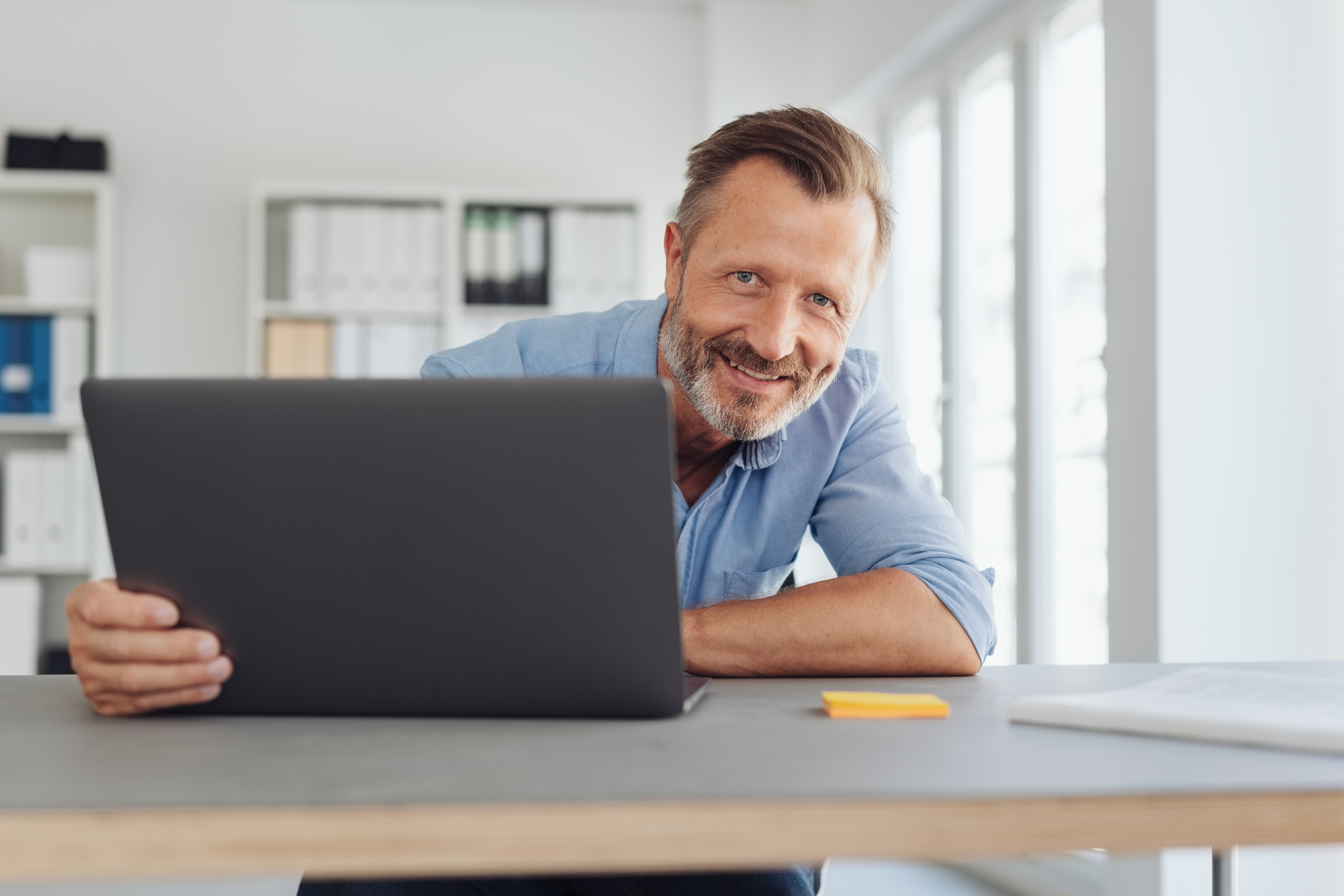 Freundlicher Mann am Schreibtisch mit Laptop