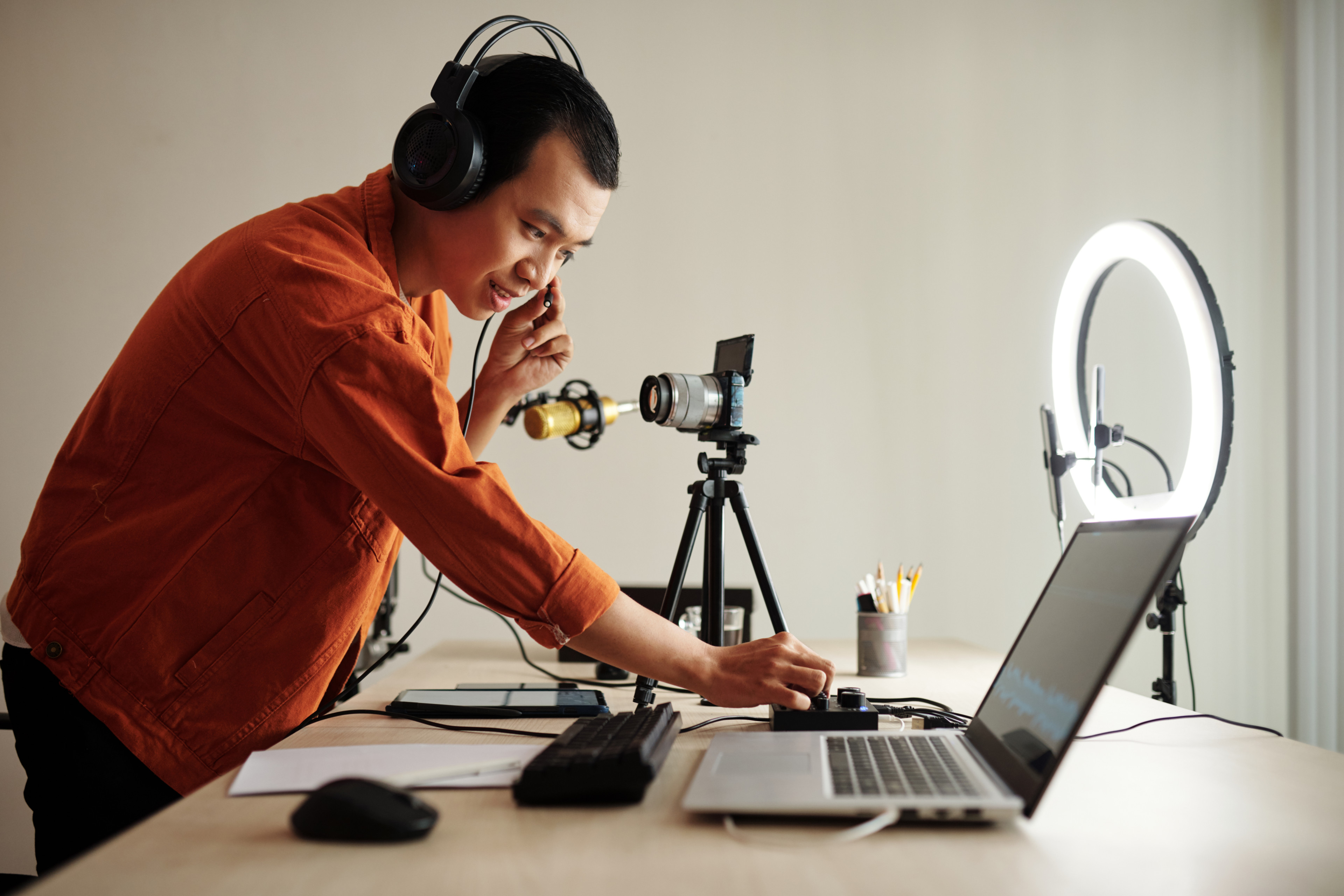 Blogger überprüft Toneinstellungen an einem Tisch mit Laptop und Mikrofon