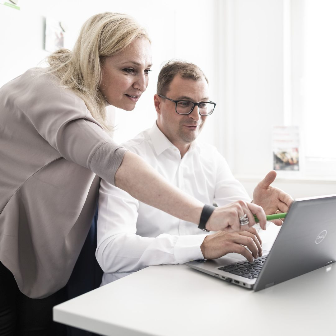Mitarbeiter der Schlüterschen diskutieren über wirtschaftliche Nachhaltigkeit am Laptop.