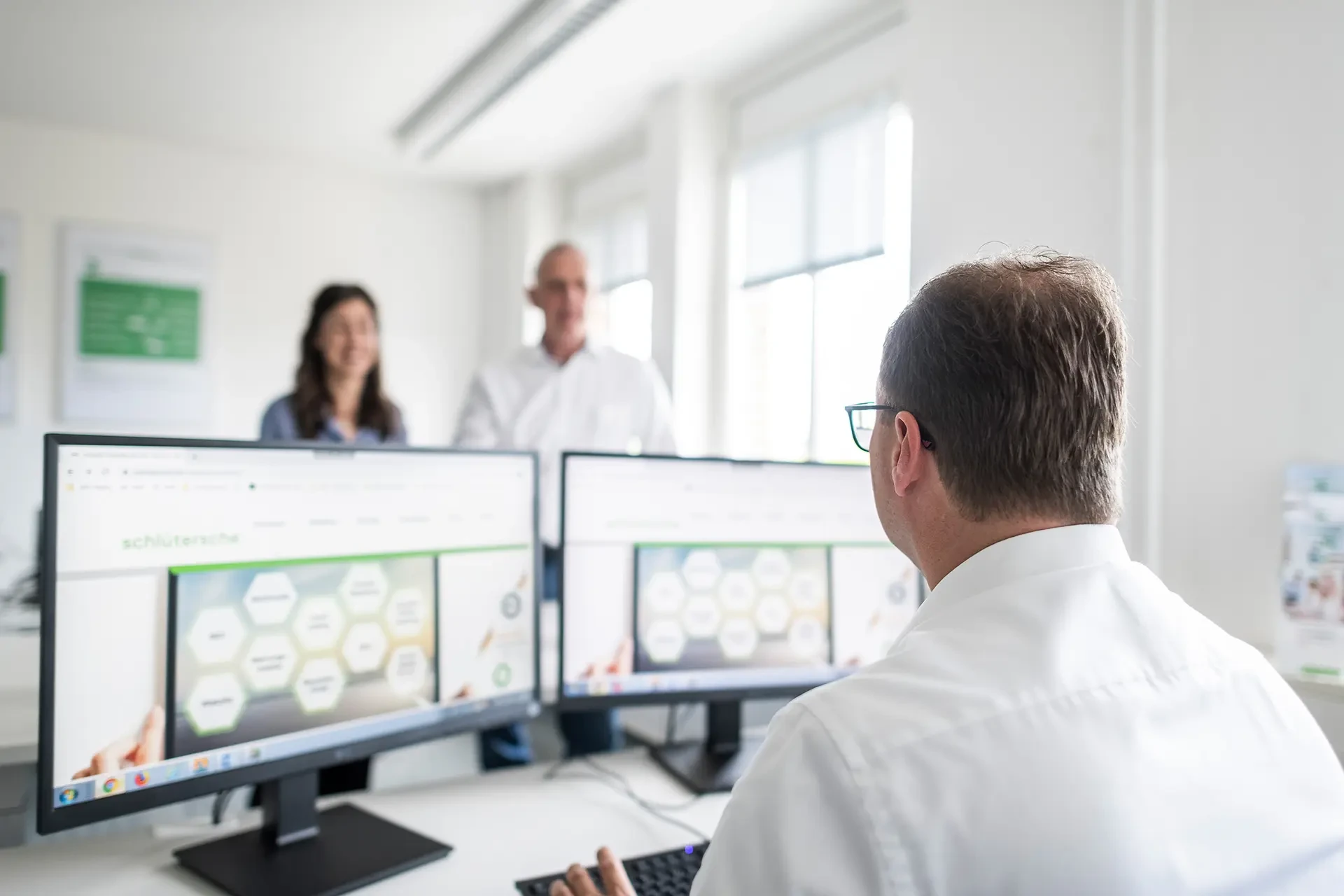 Mitarbeiter bei einem Meeting mit Computerbildschirmen im Büro