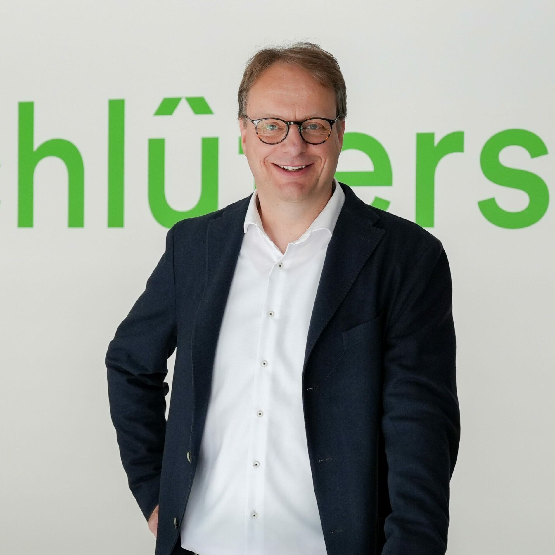Person vor einem grünen Schriftzug auf weißem Hintergrund