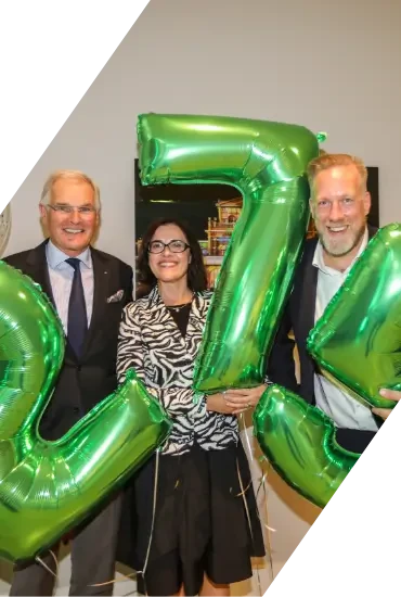 Drei Personen mit grünen Ballons in Form der Zahl 75