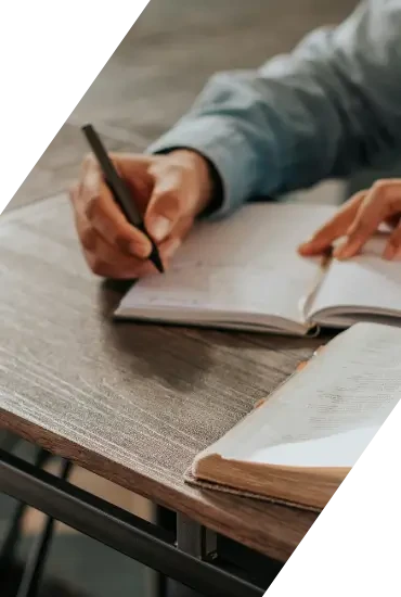 Person schreibt Notizen in ein Notizbuch auf einem Tisch