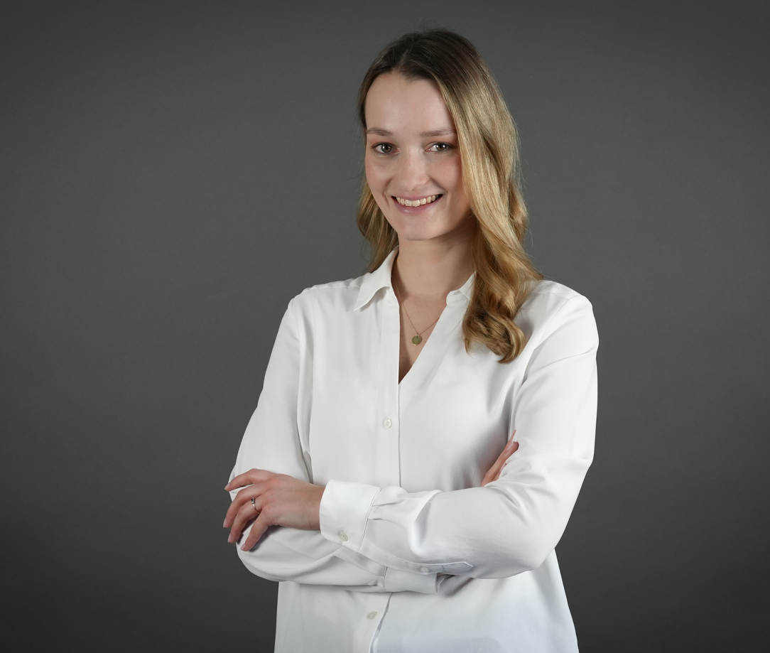 Porträt von Alicia in weißer Bluse vor grauem Hintergrund