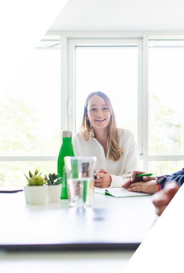 Frau in einem Meeting mit Notizbuch und Wasserflasche auf dem Tisch