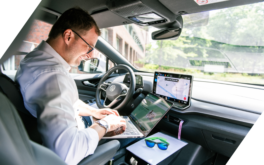 Quereinstieg: Arbeiten im Auto mit Laptop und Volkswagen-Logo Mann arbeitet am Laptop in einem Auto mit Volkswagen-Logo