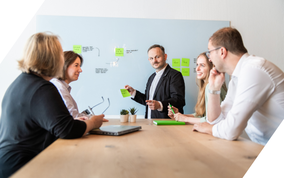 Team bei einer Besprechung mit Post-its an einer Tafel