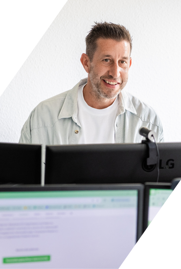 Person arbeitet am Computer mit mehreren Monitoren im Büro