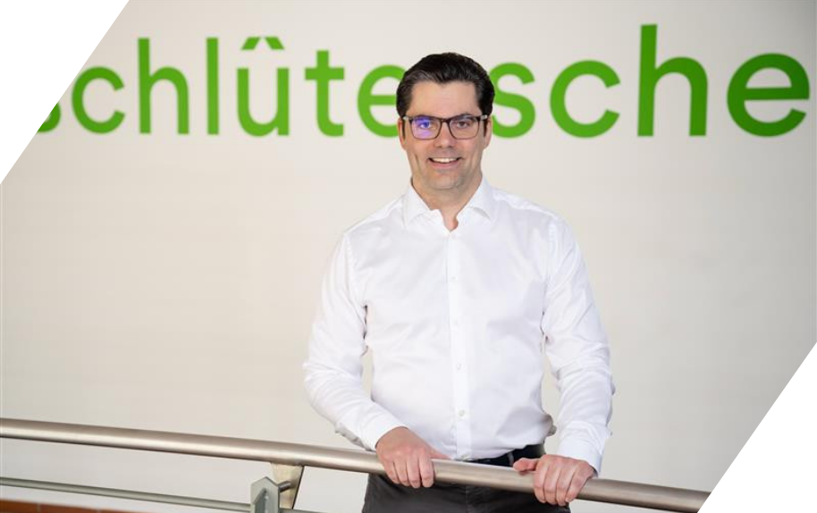 Marco Weiss steht an einem Geländer vor einer Wand mit grüner Schrift