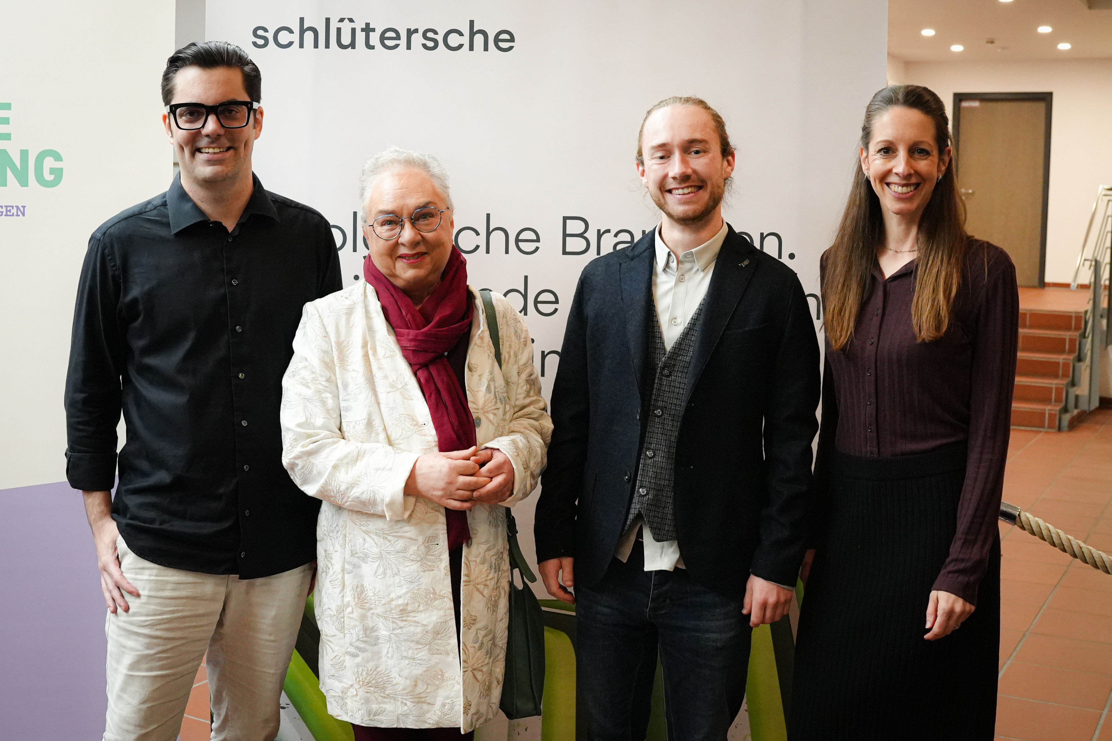 Gruppenfoto bei einer Veranstaltung der Schlüterschen Verlagsgesellschaft Gruppenfoto vor einem Banner der Schlüterschen Verlagsgesellschaft