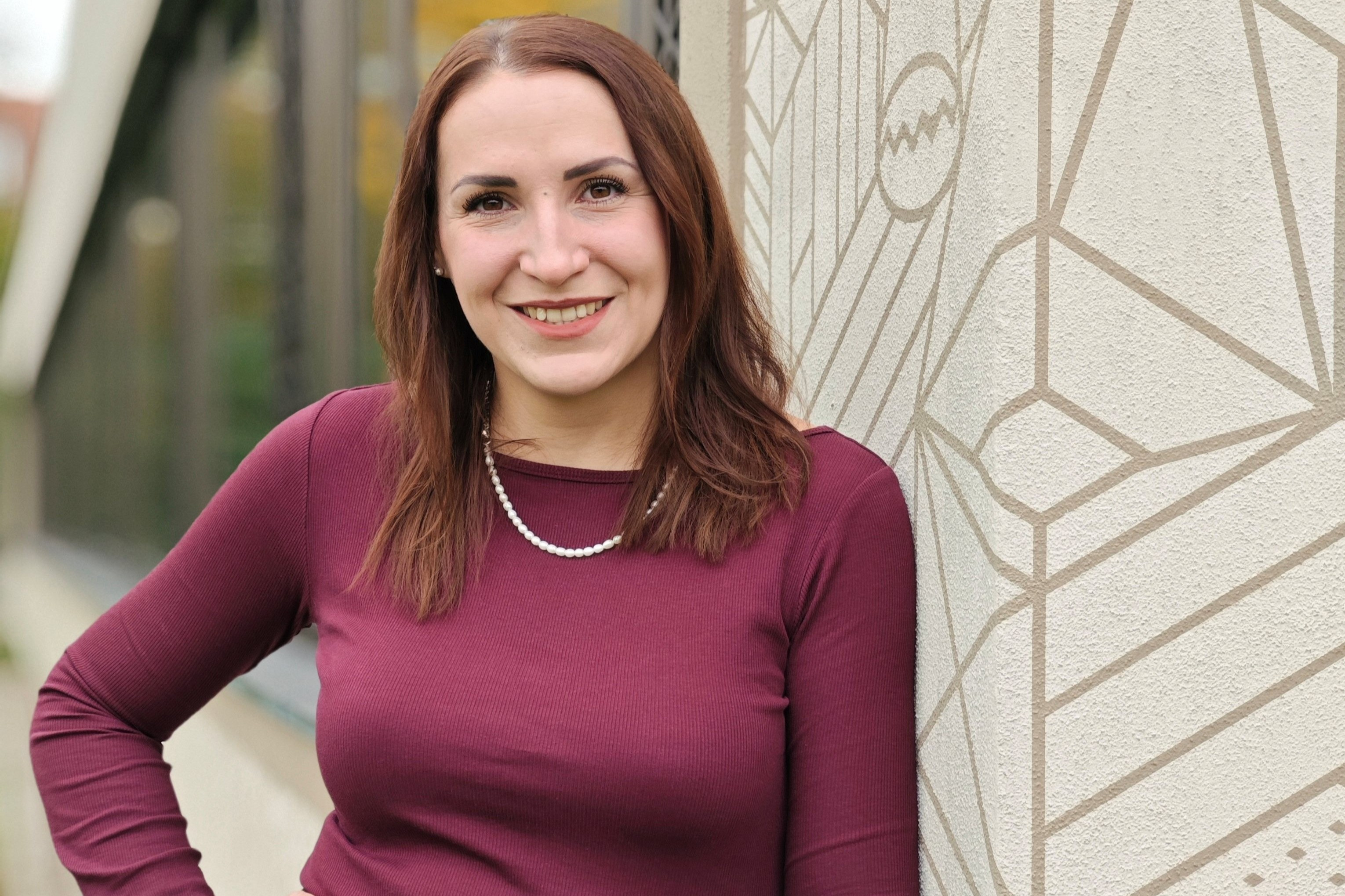 Portrait von Jennifer Karpinski vor einer Wand mit geometrischem Muster