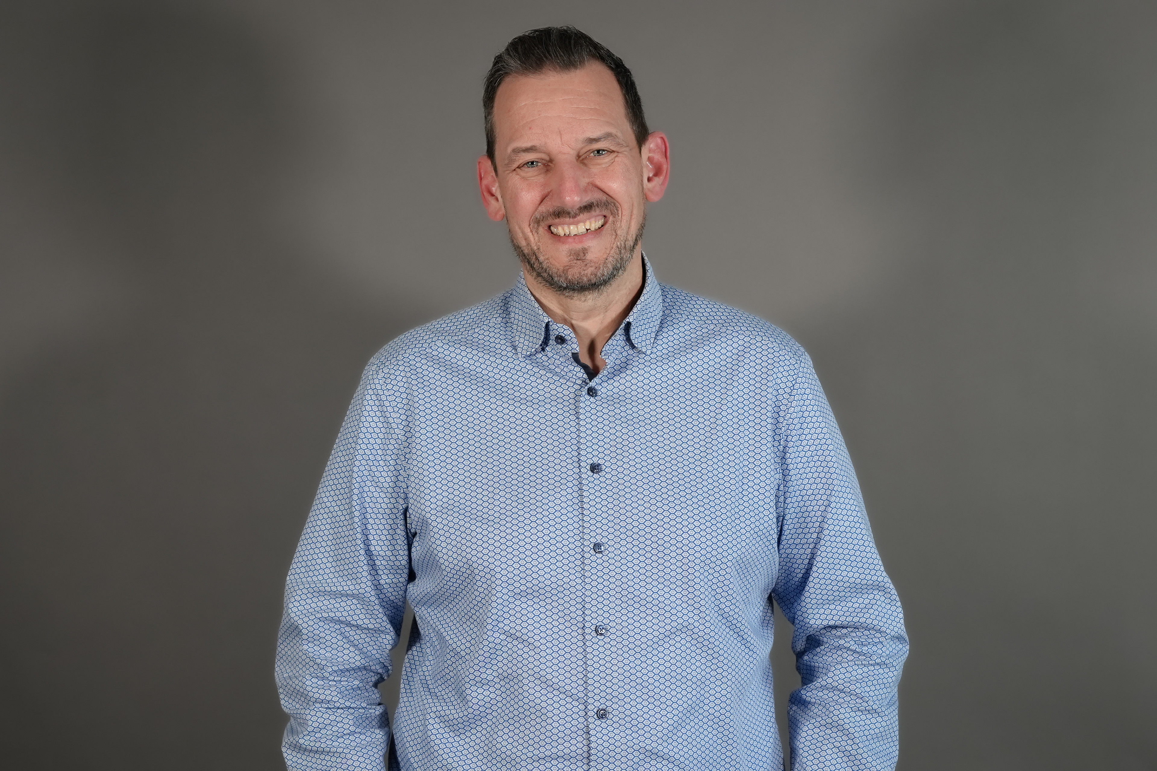 Christian mit hellblauem Hemd vor grauem Hintergrund