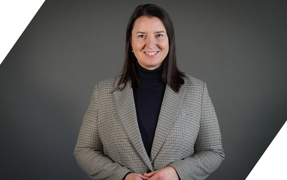 Porträt von Roksana im karierten Blazer vor grauem Hintergrund