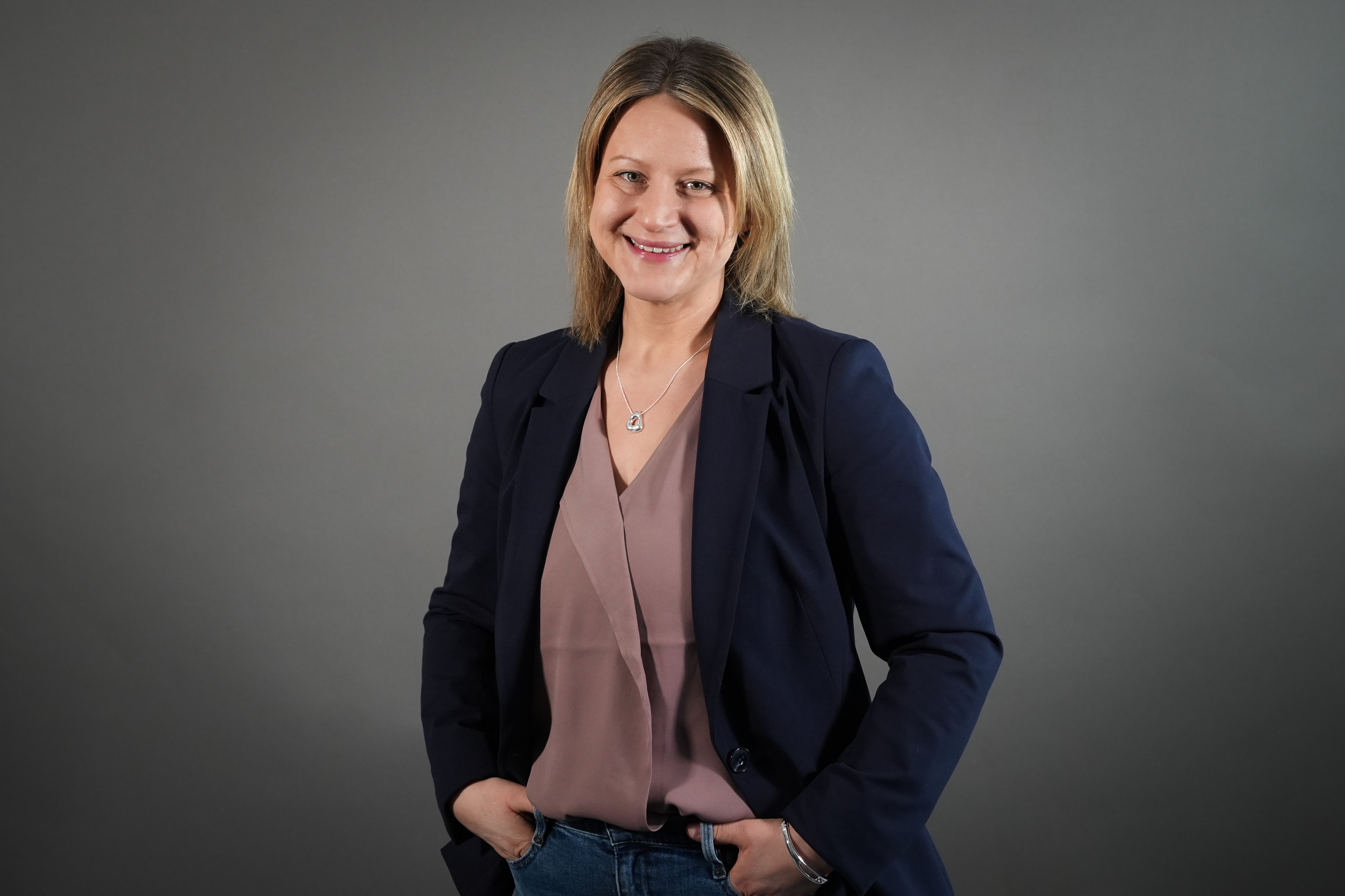 Katharina Freundorfer im Business-Outfit vor grauem Hintergrund