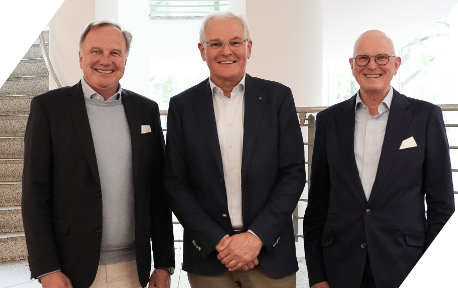 Benjamin Wahler mit Kollegen im Business-Outfit, Gruppenfoto in modernem Bürogebäude