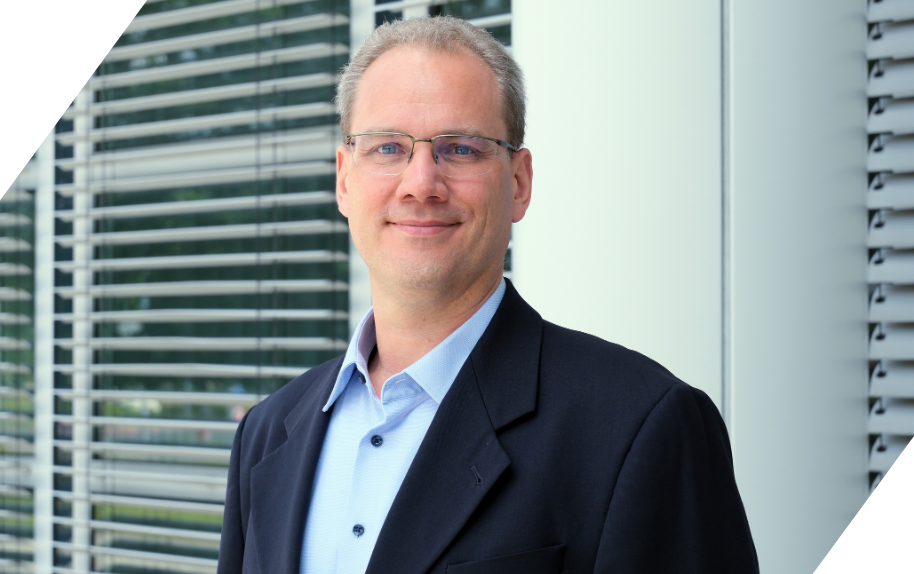 Porträt von Thomas Hortig im Business-Outfit vor einem modernen Bürogebäude