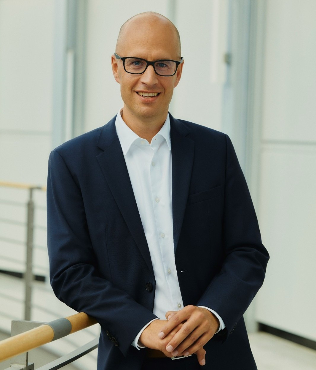 Markus John im Business-Outfit, lächelnd, vor modernem Hintergrund