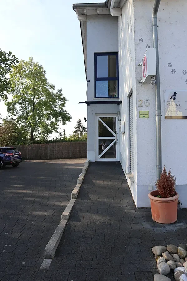 Eingang außen – Gebäudeansicht mit Parkplatz und Zugang Eingang außen eines Gebäudes mit Parkplatz und Pflanze im Topf