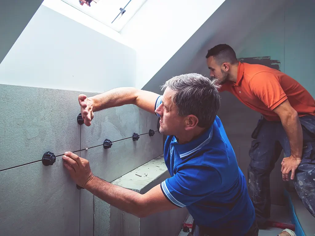 Handwerker verlegen Wandfliesen in einem modernen Badezimmer