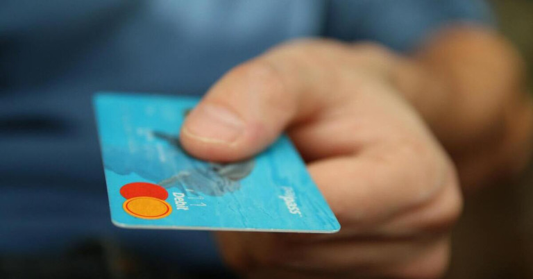 Nahaufnahme einer Hand, die eine blaue Kreditkarte hält