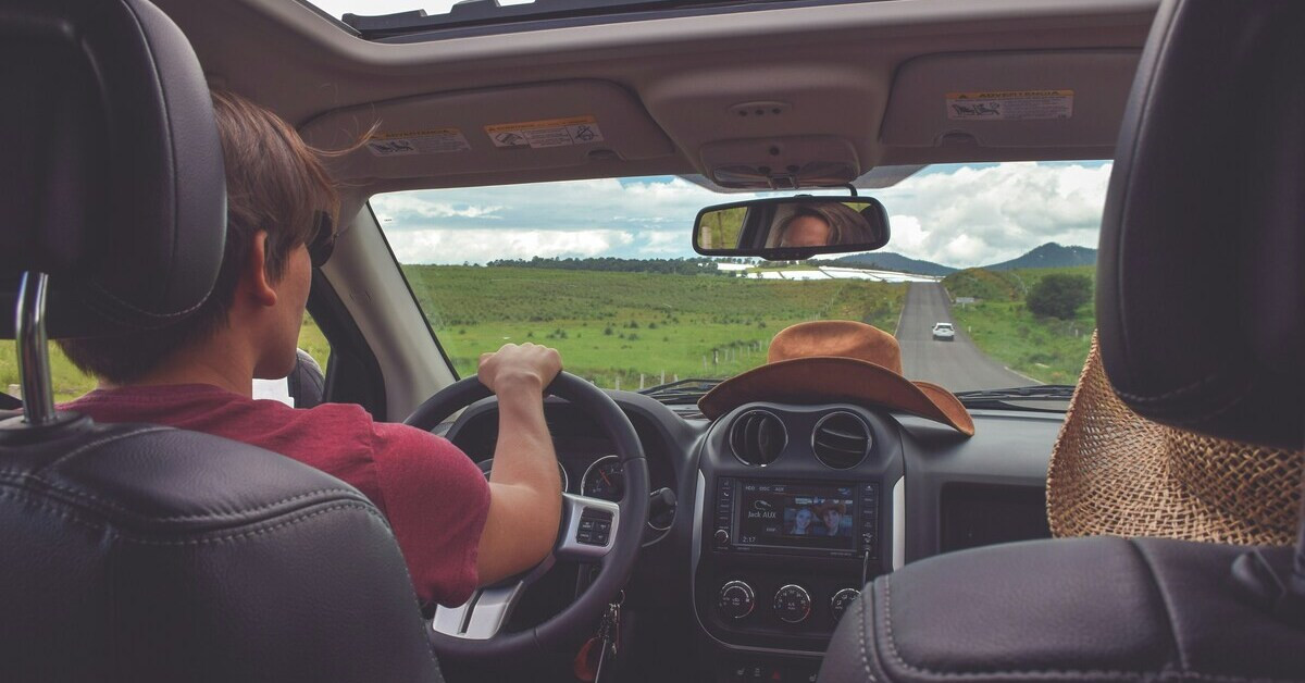Freiheit beim Fahren: Junger Fahrer auf Landstraße mit offenem Dach und weitem Blick